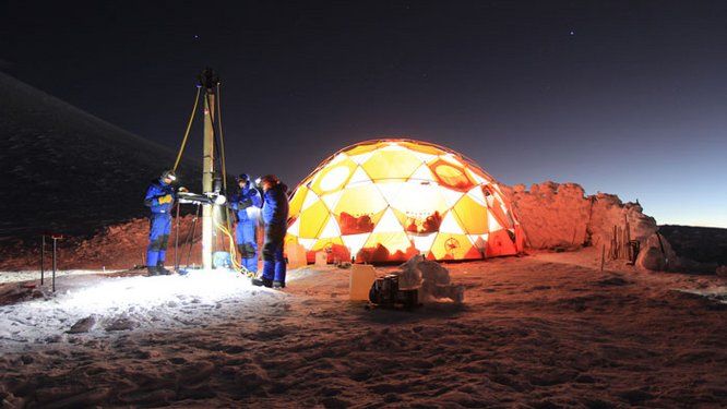 trois hommes en combinaison de nuit à côté d'un dôme lumineux