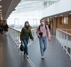 Une lycéenne et un lycéen masqués marchent dans le hall de leur lycée